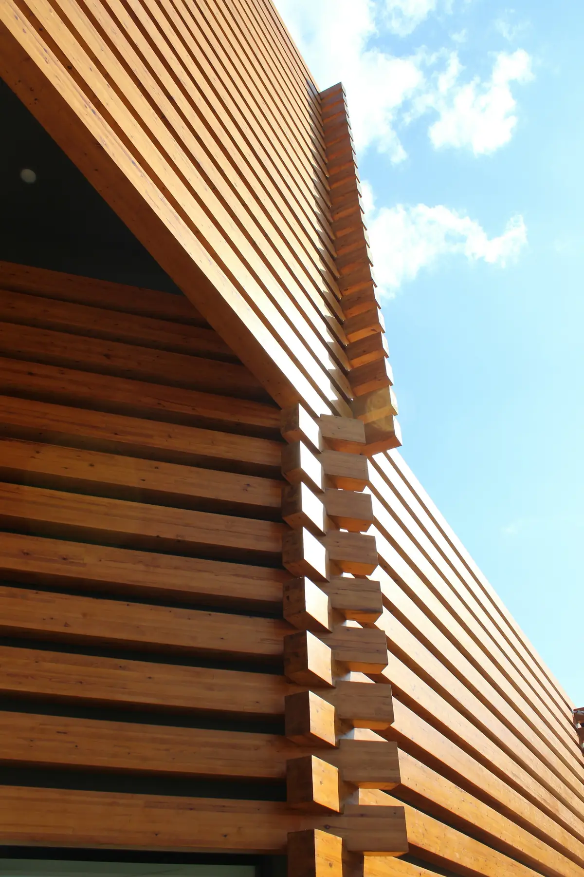 Façade habillée de lames de bois à claire-voie, en plein soleil